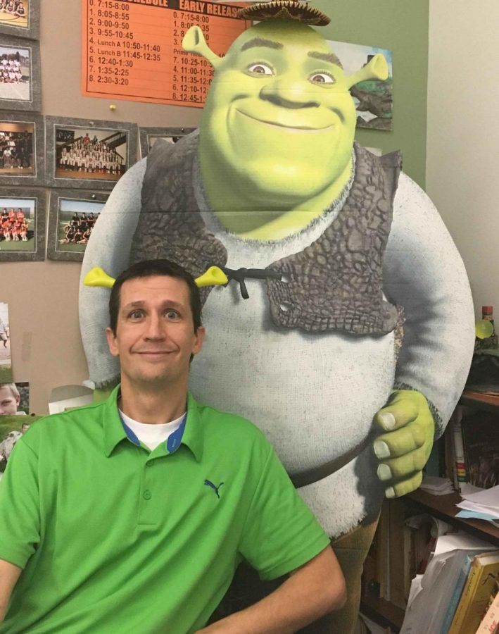 Spanish teacher Mr. Brandon Preator poses for a picture on Halloween with his Shrek costume sitting next to the cardboard cutout of Shrek the senior tennis players purchased for him.