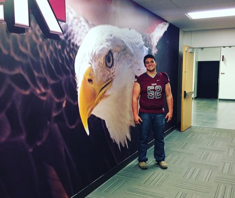 Max Gallagher stands in front of a painted wall while visiting Chadron State in Nebraska.