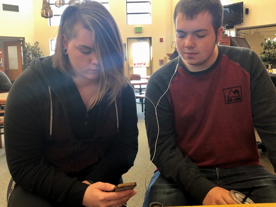 Powell High School students, junior Bayli Voss (left) and senior Dominic Johnson, listen to music in the library during their free time.