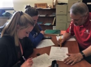 Mr. Schwahn helps Hailee Hyde and Isabella Wambeke with a math problem.
