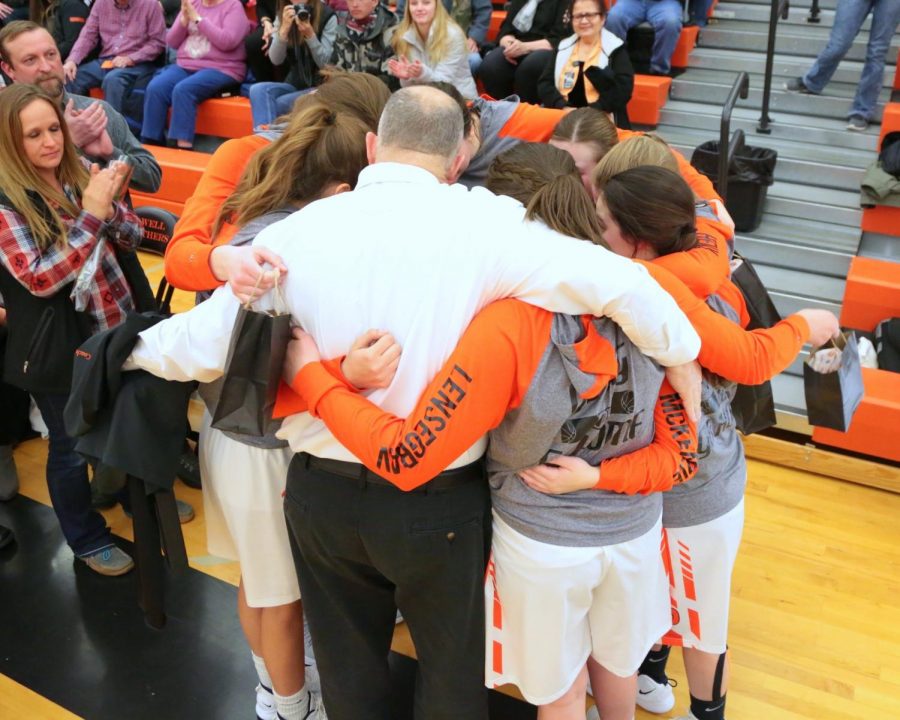 The Lady Panther basketball team has a group hug with Coach Mac on their senior night earlier in the season