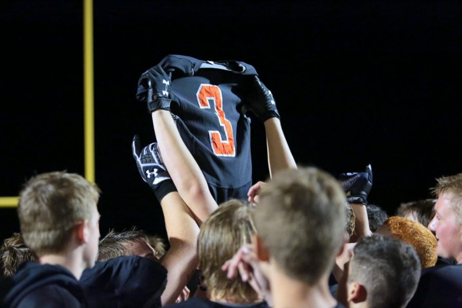 The+Panther+football+team+hoists+Ethan+Asher%E2%80%99s+jersey+in+the+air+during+the+game+Friday+night+against+Worland.