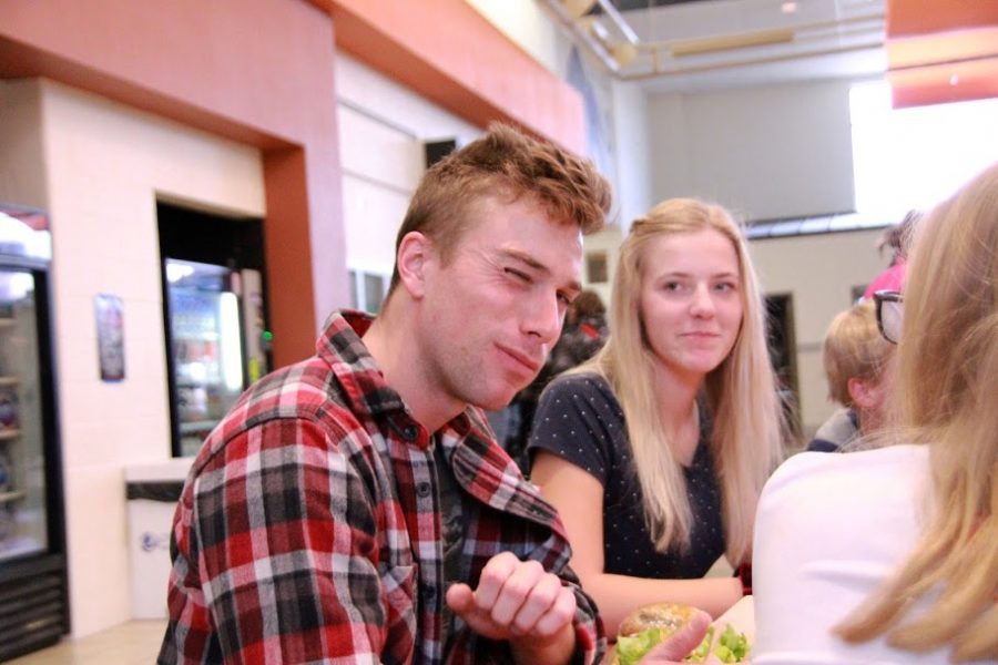 Sam Douglas winks at the camera after taking a large bite of his salad.