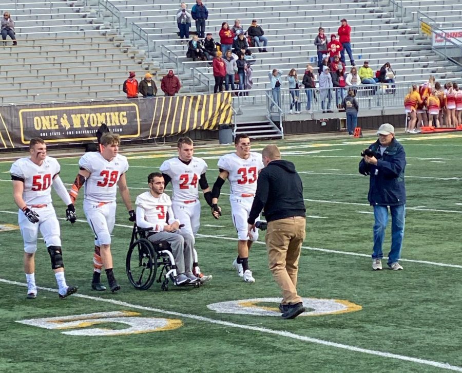 The Powell High School football captains walk hand in hand with teammate Ethan Asher from the captains meeting before the 3A state game