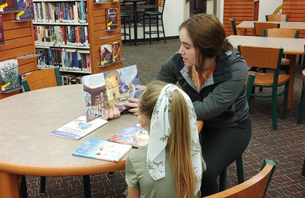 Sophomore Traci Guiterrez reads a Dr. Seuss book to a little girl who attended the Bingo for Books night at PHS.  