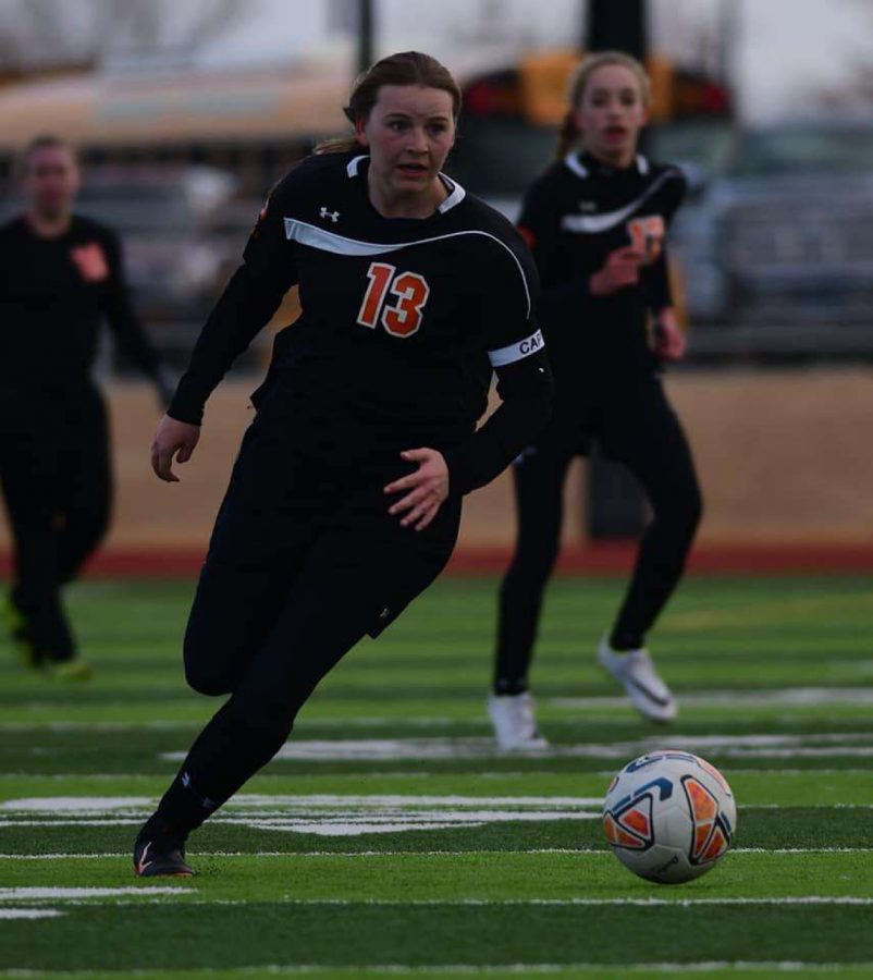 Senior Michele Wagner dribbles the ball upfield, followed by two of her teammates.