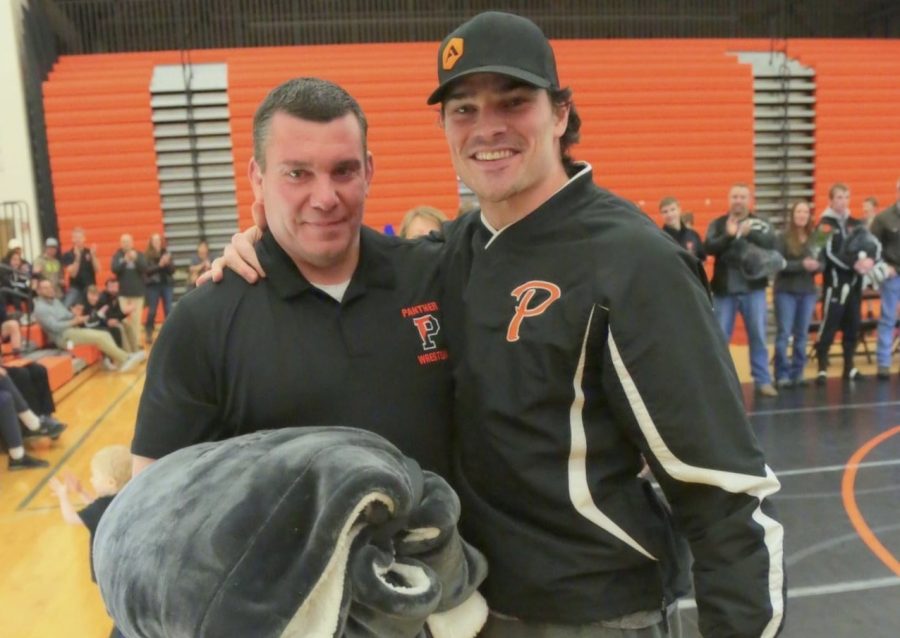 Former Panther wrestler Olie Olsen (right) was on hand to surprise Mr. Nate Urbach and present him with a retirement blanket during Urbach’s final meet in the Panther Gym in February. 