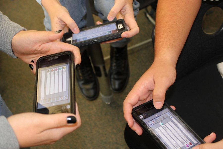  Students hold their phones together while they play popular mobile game, Among Us