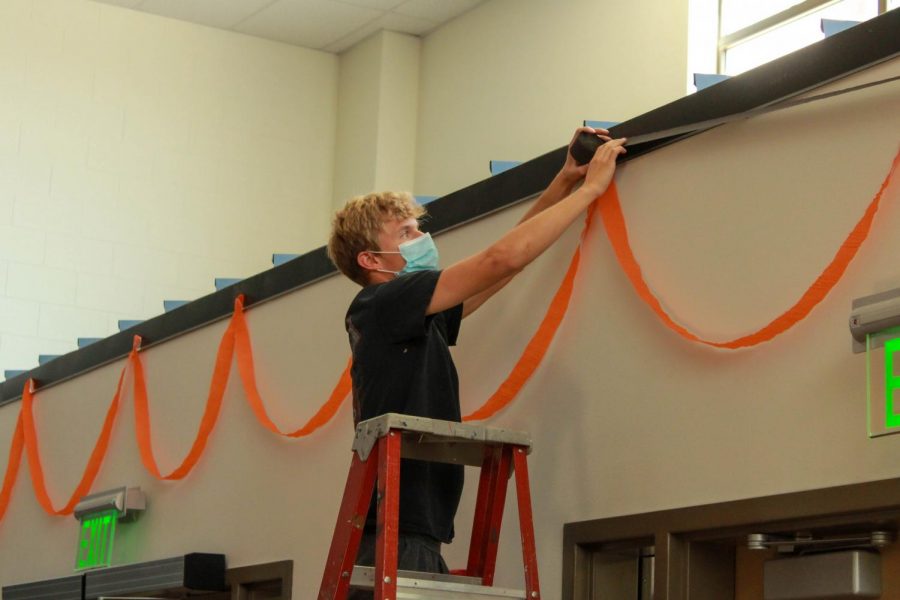 PHS junior Keaton Rowton hangs streamers over the entryway in the commons for Homecoming week in September. Student Council focused on decorations and dress-up days during 2020 Homecoming due to the lack of events taking place because of COVID-19.