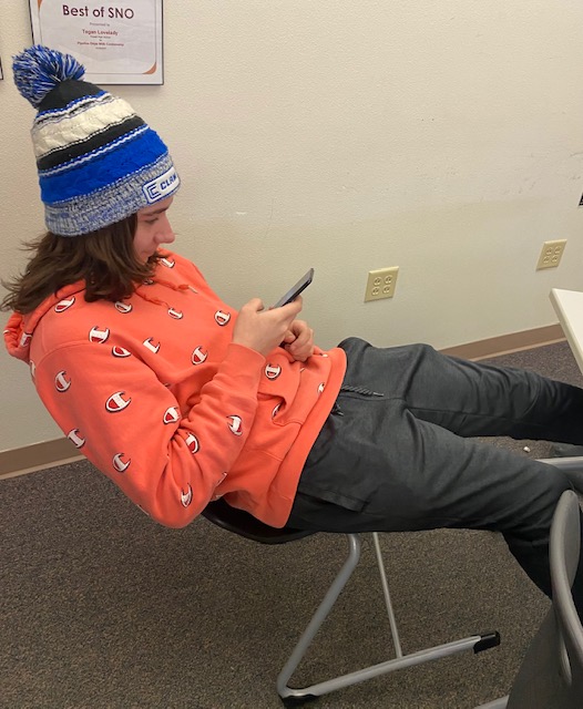 PHS senior Tristan Willett leans back in his chair and plays on his phone while wearing his beanie, which is against the school’s dress code. He’s one of many high school students who haven’t been able to shake the “mid-semester slump” since the third grade. 