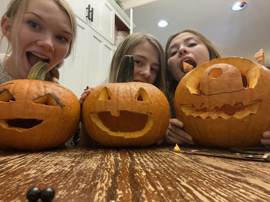 (From left) Juniors Sydney Hull, Taryn Feller, and Alexis Terry pretend to take bites of their newly carved pumpkins from the 2020 Halloween year.