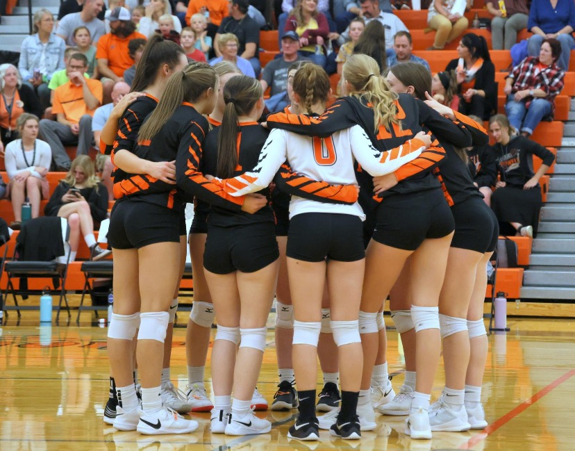 The+Lady+Panther+volleyball+team+stands+in+a+huddle+after+a+play.