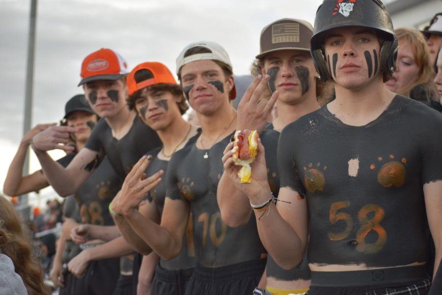 A group of high school boys painted up for the homecoming game, decked out in the iconic orange and black school colors. 