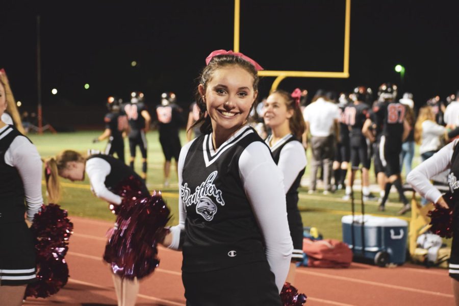 PHS Junior Bella Bertagnole avidly moves her pom poms in greeting to cheer on the football team for the Breast Cancer Awareness game. 