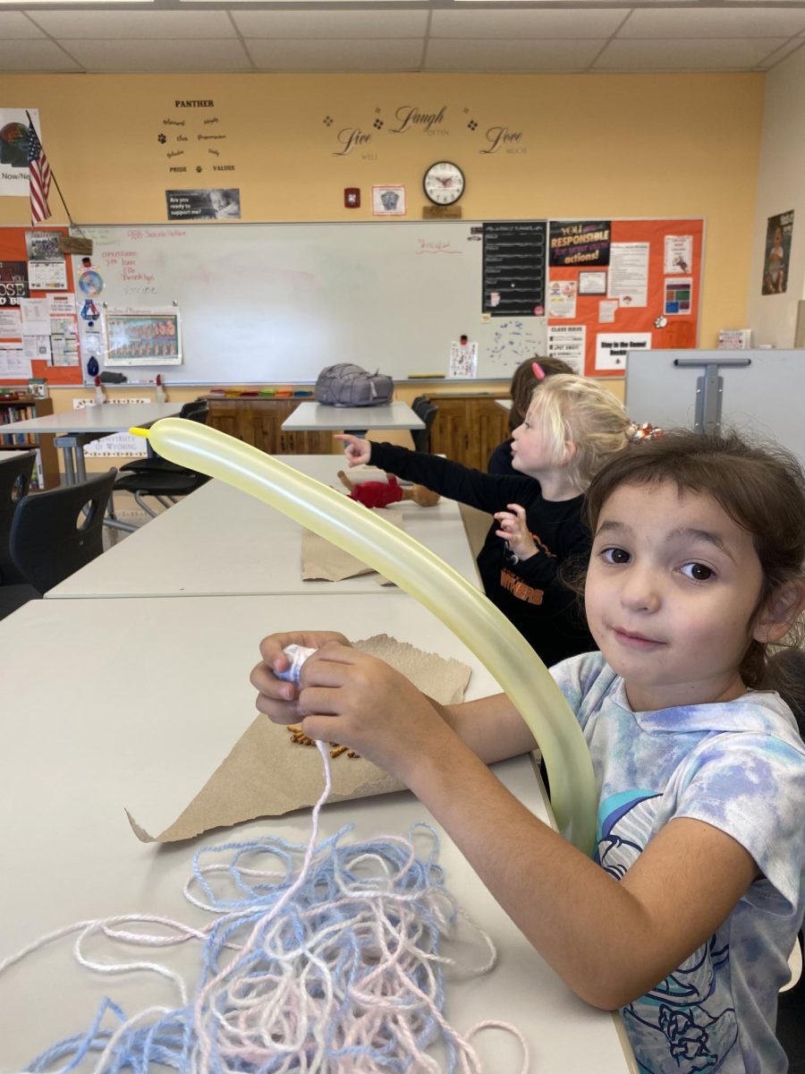 The young girl smiles for the camera, mid-creation of her balloon animal. 
Photo Courtesy of Kendal Eden.