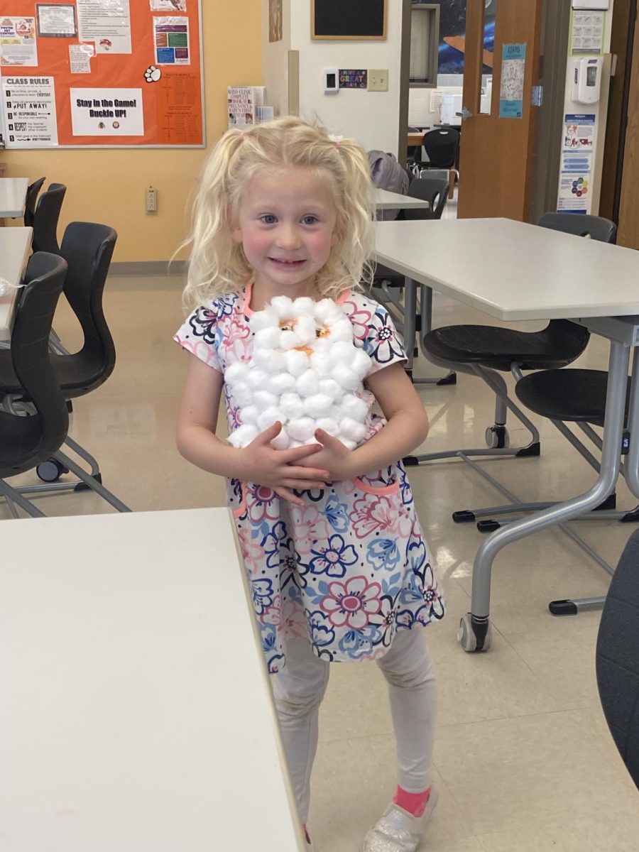 A young child smiles in pride, displaying her creation.
Photo Courtesy of Kendal Eden.