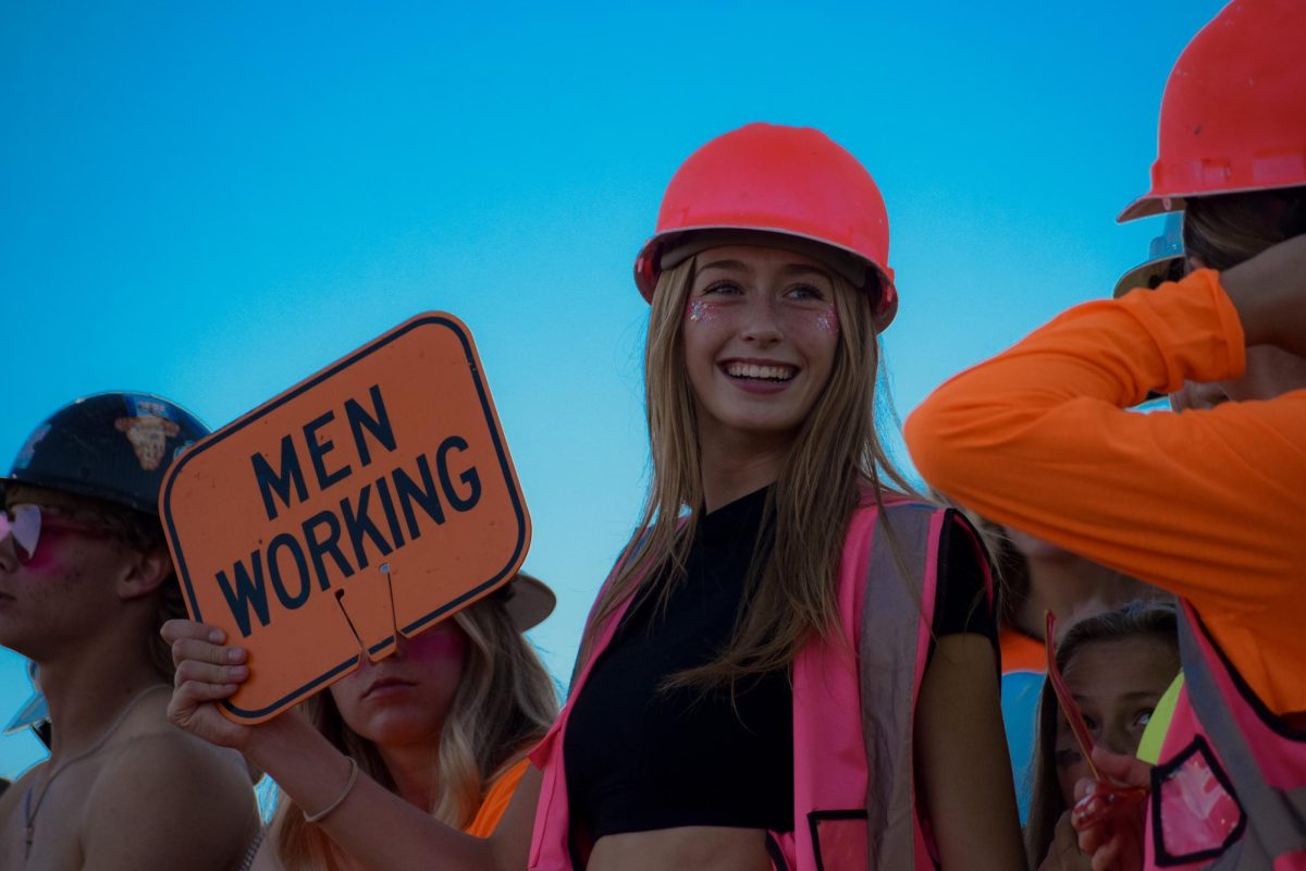 Decked out in construction hard hats and reflective vests, PHS senior Addy Thorington smiles at her friends, cheering on the Powell Panther Varsity football team who would later go on to win against the Douglas Bearcats 47-7.