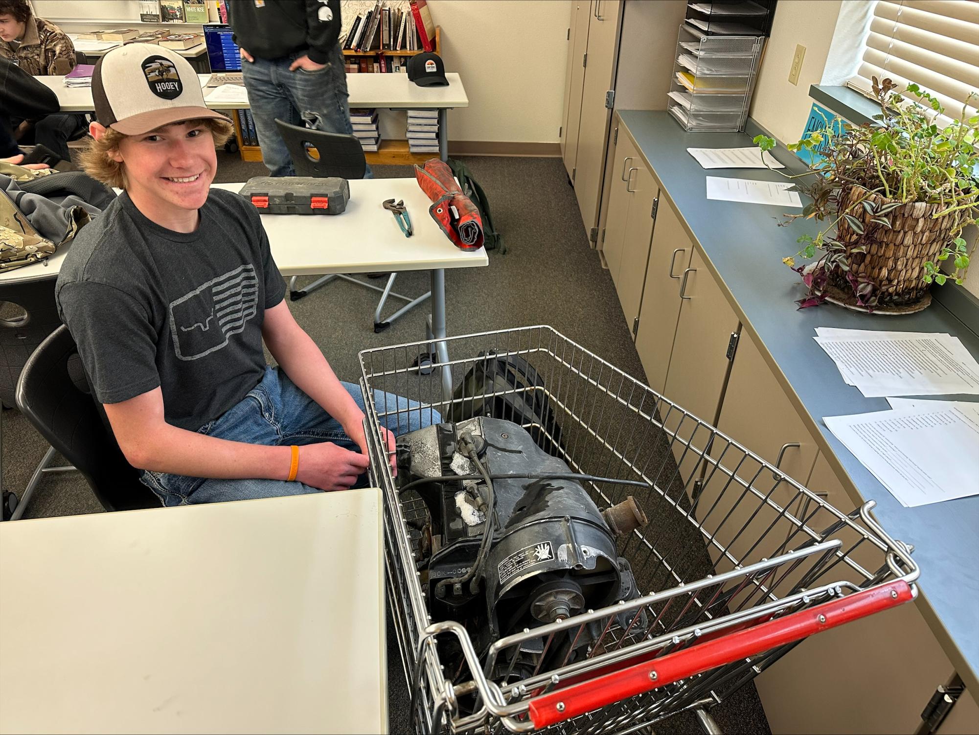 Weston Thompson proudly poses with his work-in-progress go-kart that he brought to school to work on.  