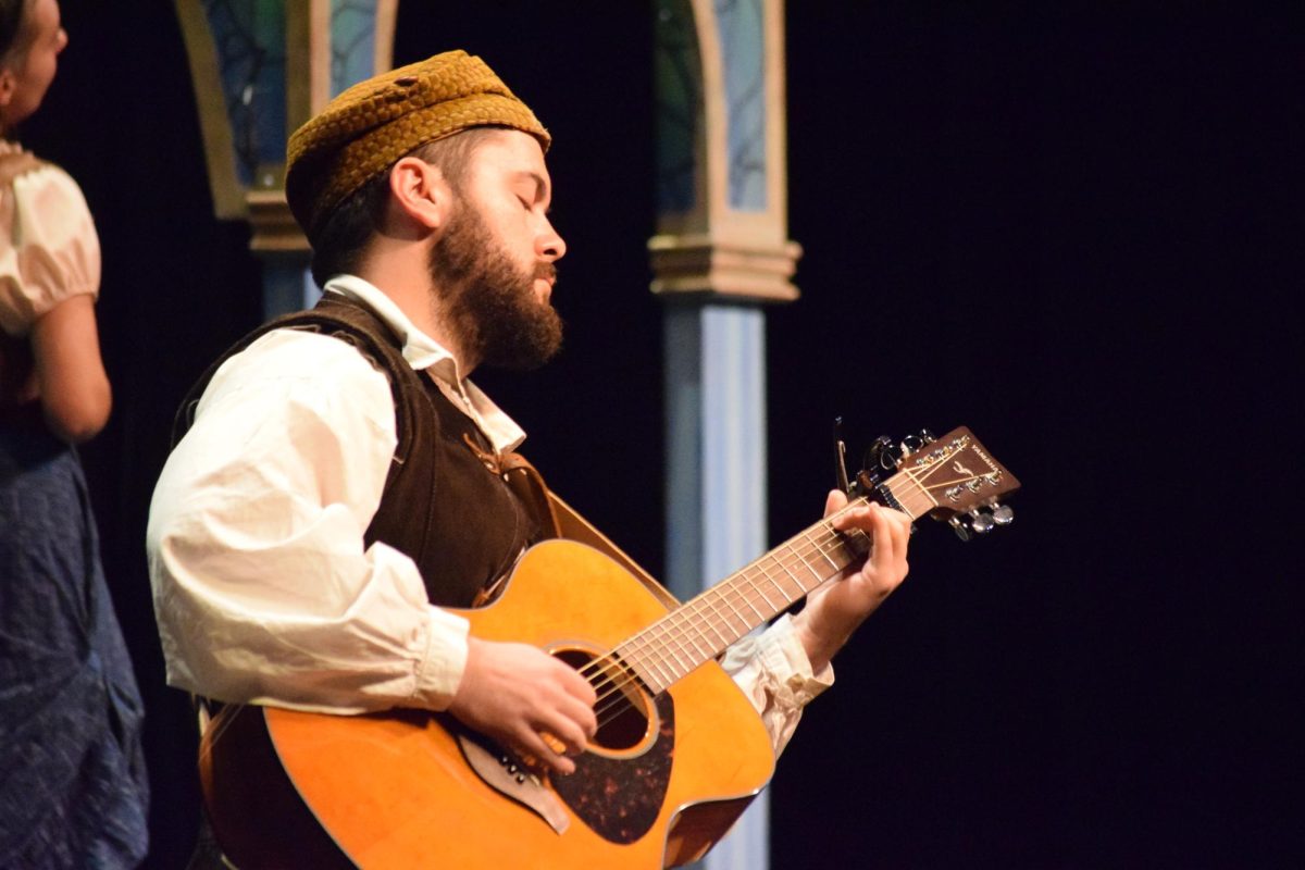 The actor from Shakespeare in the schools strums his guitar.