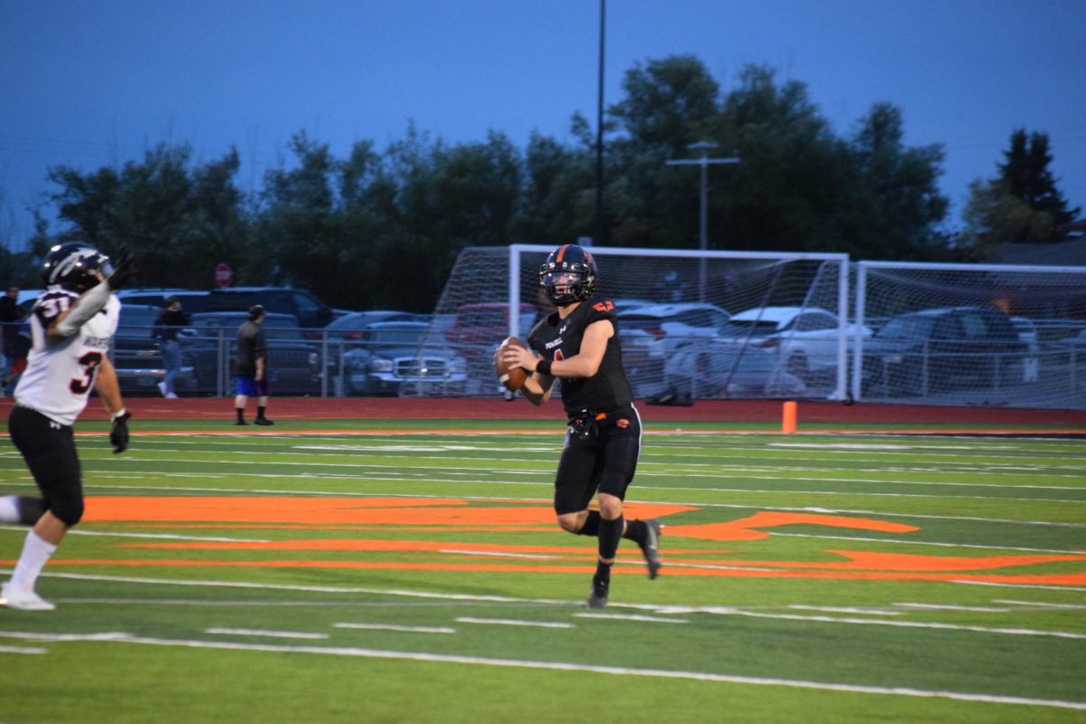 Senior and quarterback Jhett Schwahn looks up the sideline for a quick pass after a Worland player breaks through the line of scrimmage. 