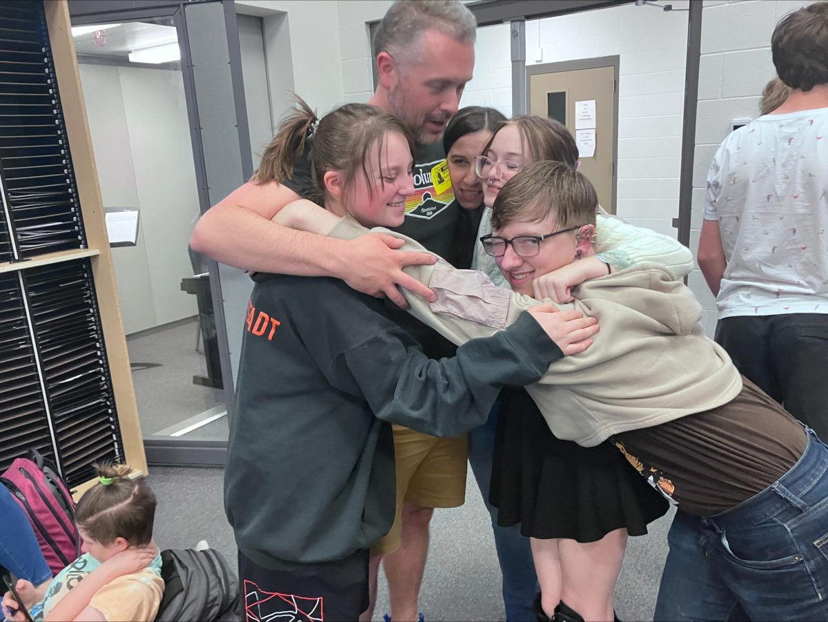 Students hug Mrs. Schoessler and her husband during their choir class.