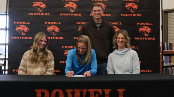 Kenna Jacobsen signs with her sister Ashlee, mother Jamie, and brother Aidan smiling nearby.