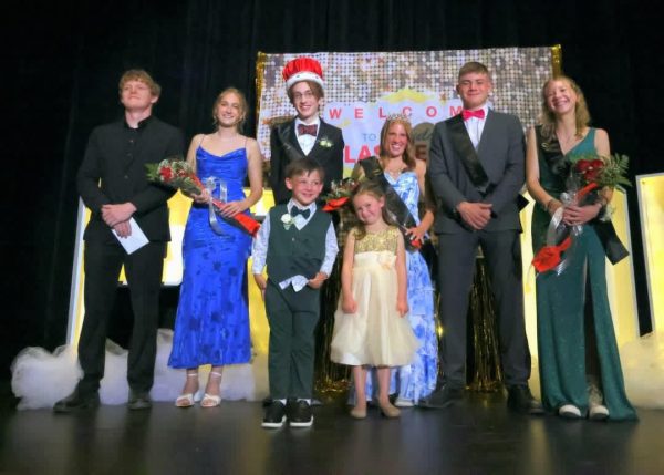 Students who received prom royalty take a picture on the stage with their sash and flowers.