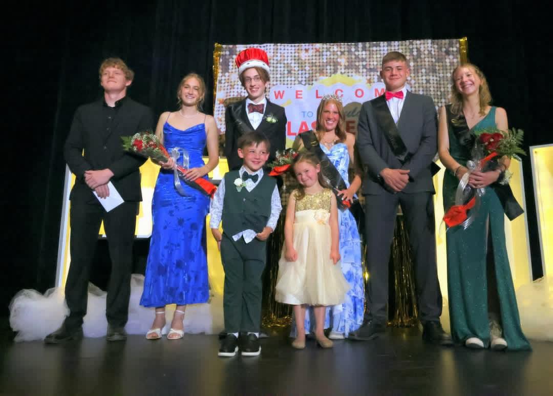 Students who received prom royalty take a picture on the stage with their sash and flowers.