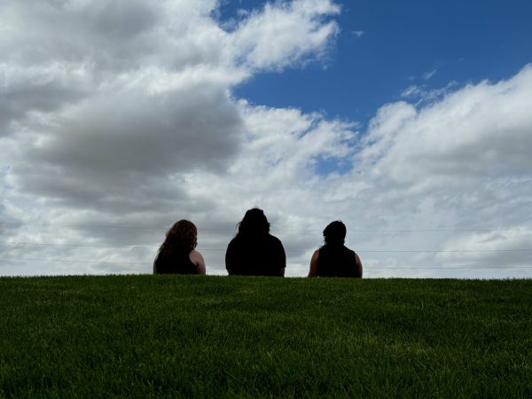 Ashton McDaniel, Deeanna Gibson, and Casey Thormahlen sit on a hill outside Powell High School and ponder. 