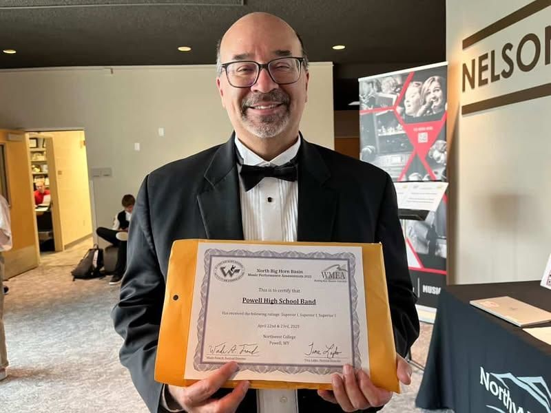 John Fabela proudly poses for a photo, holding the band’s Superior Rating award.
