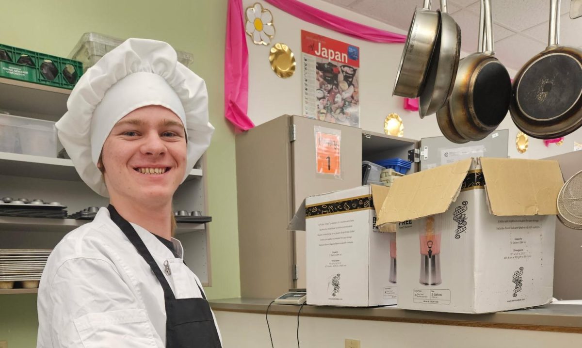 Head Chef Alex Watts smiles happily into the camera while baking in Mrs. Culwell's room.