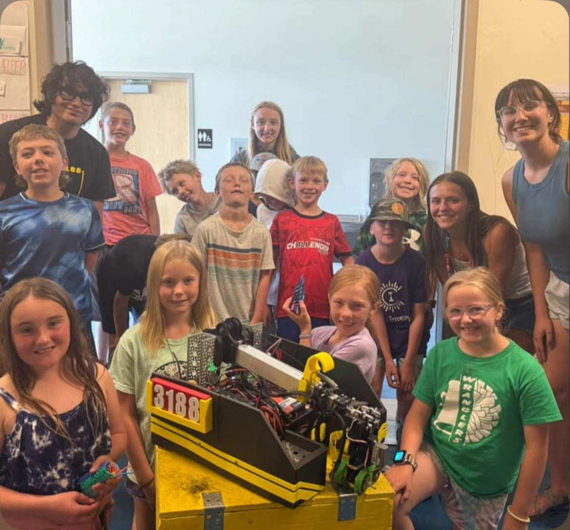 Members of the robotics team pose next to the elementary school students who experienced the wonder of STEM.