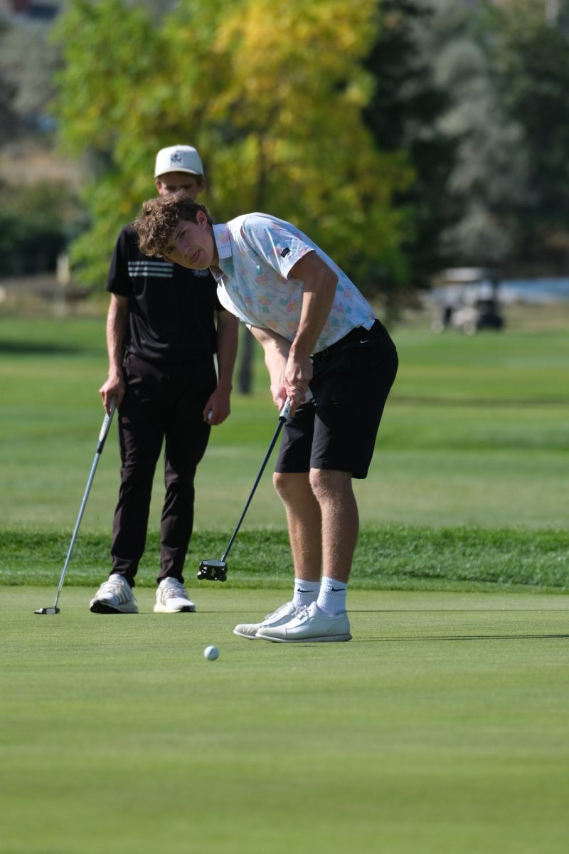Sophomore Kason Sherman watches a putt as it rolls across the green.