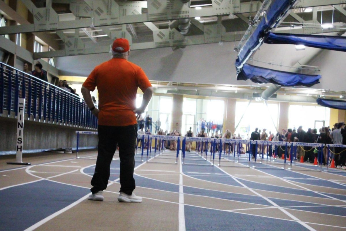 Coach Scott Smith awaits the start of the 55m hurdle race. 