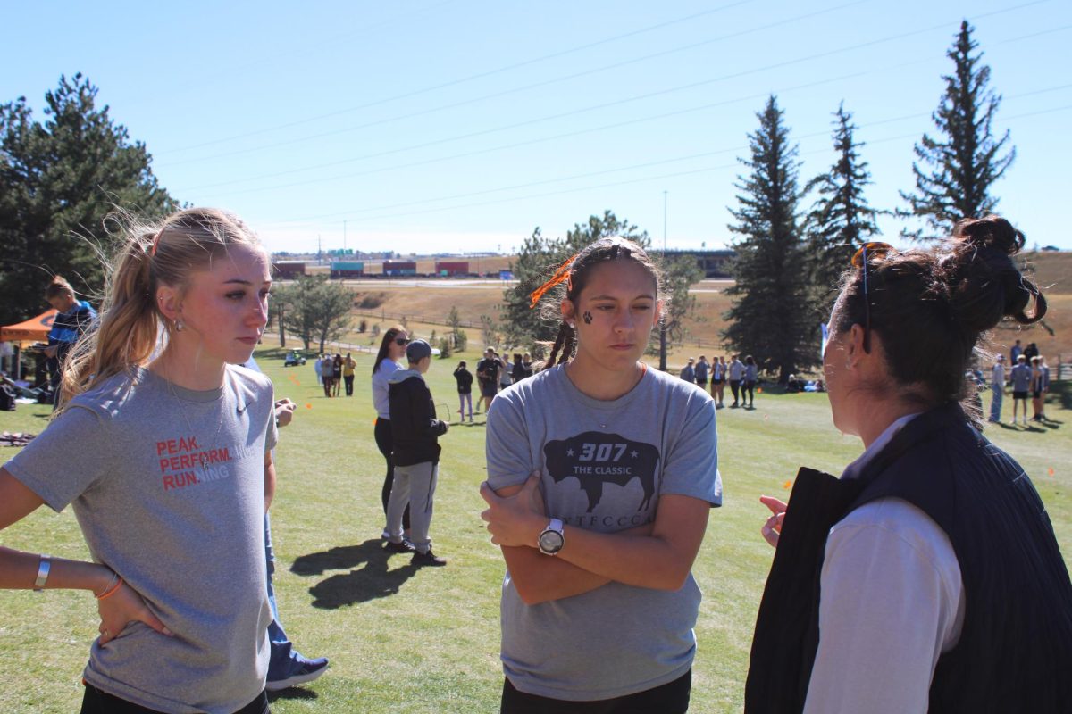 Runners Karee Cooley and Shelby Zickefoose strategize with Coach Rachel Carlson before the state race
