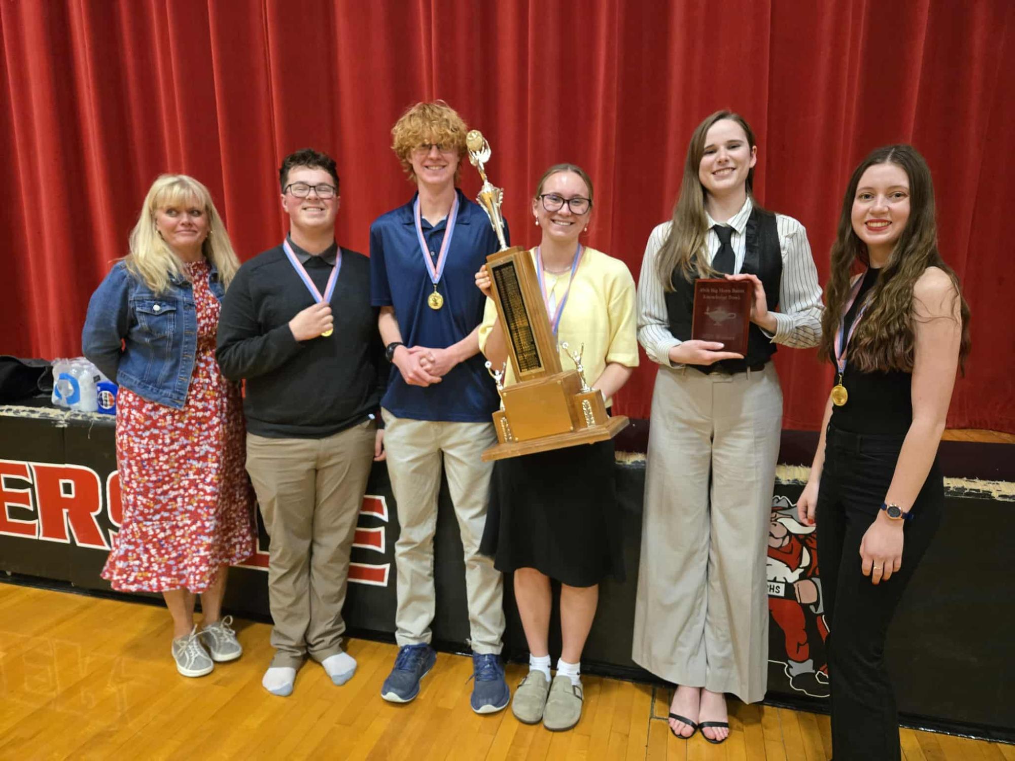 The 2025 Knowledge Bowl Champions (Left to Right) Coach McArthur, Curtis Meucke, Colin Walker, Audrey Johnson, Katerina Reitz, and Natalie Black pose with their trophy.