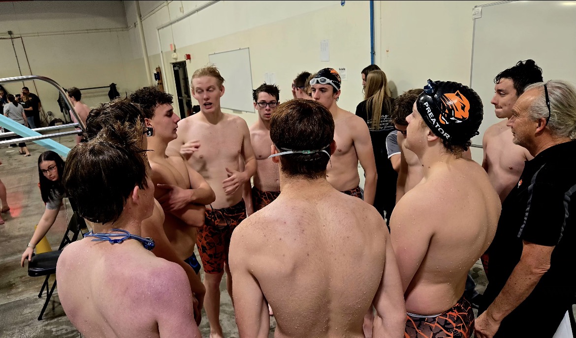 Senior Hugh Carpenter gives a pep talk as the swim team huddles together between heats.