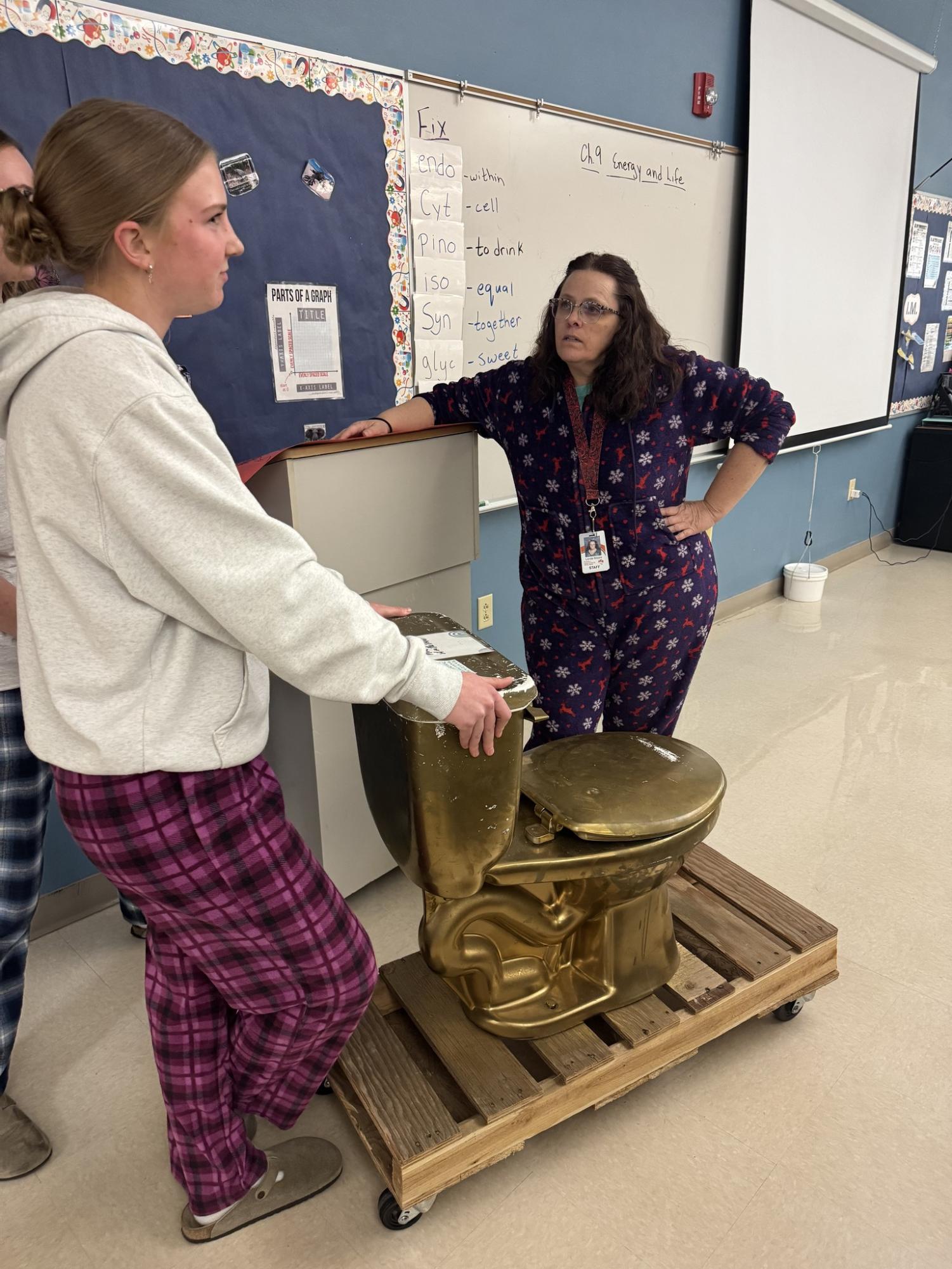 Ashlee Jacobsen and Lenita Moore gather around the Make-A-Wish week golden toilet.