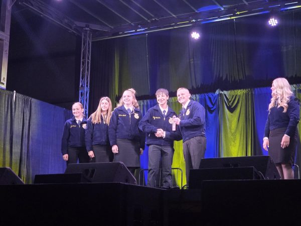 Left to Right: junior Tanis Ginest, freshman Brooklyn Kyniston, freshman Autumn Allred, freshman Blake Bessler, and 25-26 state parliamentary handing ribbons to the wool judging team
(Courtesy Photo)